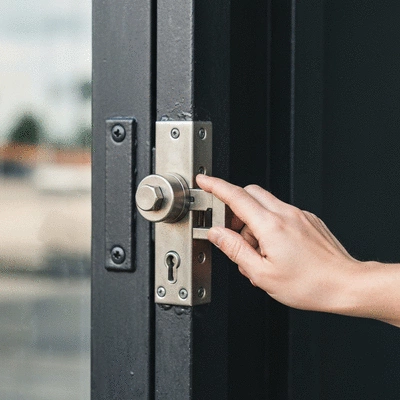 Gros plan d'une main testant une serrure multipoints renforcée sur une porte sécurisée